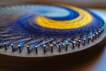 Colored thread mandala on a wooden board with nails. Mandala Moon Harmony Sun esotericism and psychology pictures from yellow and blue silk threads.の写真素材