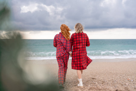 Sea two Lady in plaid shirt with a christmas tree in her hands enjoys beach. Coastal area. Christmas, New Year holidays concepの写真素材