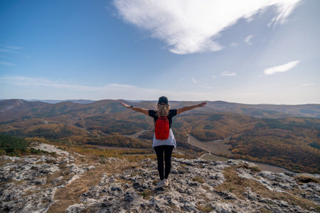 woman backpack on mountain peak looking in beautiful mountain valley in autumn. Landscape with sporty young woman, blu sky in fall. Hiking. Natureの写真素材