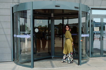 woman entering a supermarket. Caucasian model with long brunette hair, wears sunglasses and a khaki dress.の写真素材