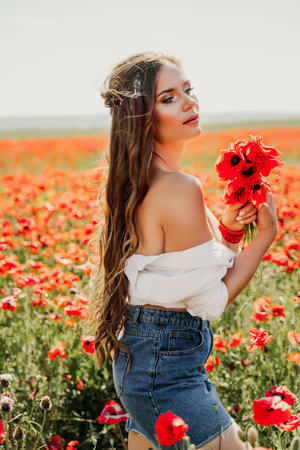 Woman poppies field. Side view of a happy woman with long hair in a poppy field and enjoying the beauty of nature in a warm summer day.の写真素材