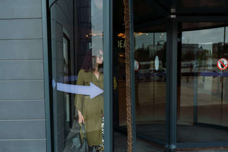 Woman leaves a supermarket. Caucasian model with long brunette hair, wears sunglasses and a khaki dress.の写真素材