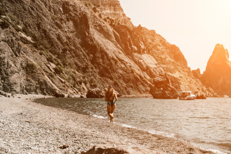 Woman travel summer sea. A happy tourist in a blue bikini enjoying the scenic view of the sea and volcanic mountains while taking pictures to capture the memories of her travel adventure.の写真素材