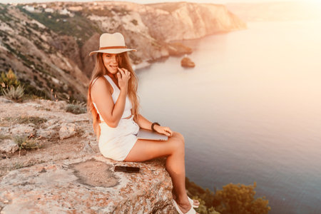 Freelance women sea working on the computer. Good looking middle aged woman typing on a laptop keyboard outdoors with a beautiful sea view. The concept of remote work.の写真素材