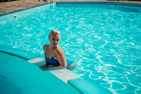woman swimming pool. happy woman with wet hair and stylish sunglasses sunbathing in pool