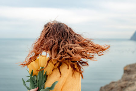 Portrait of a happy woman with hair flying in the wind against the backdrop of mountains and sea....
