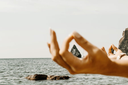 Yoga on the beach. A happy woman meditating in a yoga pose on the beach, surrounded by the ocean and...