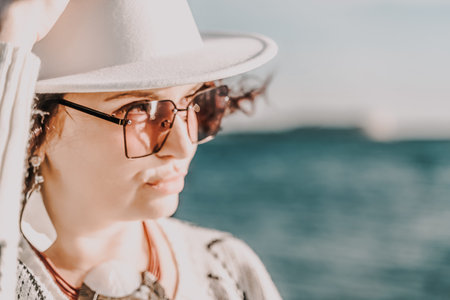 Portrait of a curly haired woman in a white hat and glasses on t