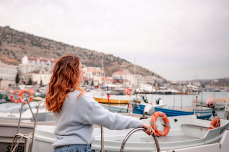 A woman stands in front of a row of boats, some of which have orange life preservers on them. The scene is peaceful and serene, with the boats and the woman creating a sense of calmness and relaxation.の写真素材