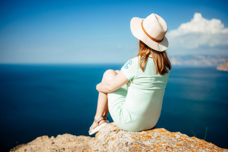 A woman is sitting on a rock overlooking the oceanの写真素材