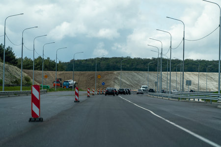 A road with a red and white cone on the side of it. The road is empty and there are no cars on it.の写真素材