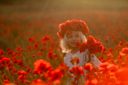 A young girl is standing in a field of red poppiesの写真素材