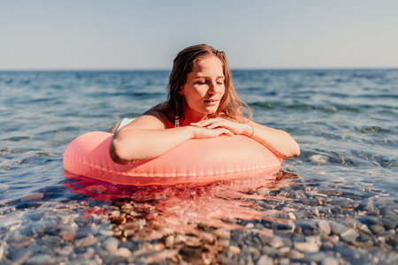 A woman is laying on a red inflatable ring in the oceanの写真素材