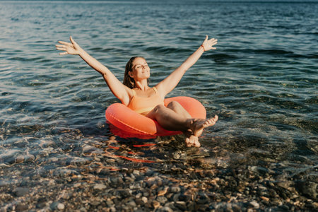A woman is floating in a red inflatable raft on a body of waterの写真素材