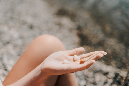 A person is holding a handful of nuts in their hand. The nuts are of different sizes and shapes, and they appear to be almonds. The person seems to be enjoying the nuts and is likely to eat them soon.の写真素材
