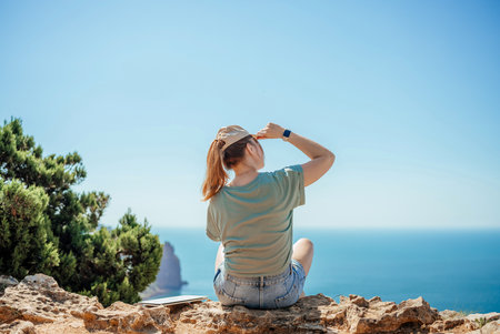 A woman is sitting on a rock overlooking the oceanの写真素材