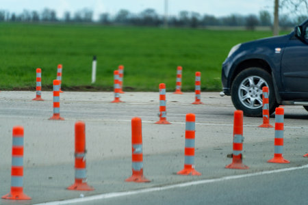 A row of orange and white traffic cones are lined up on a road. The scene is quiet and peaceful, with no cars or people in the area.の写真素材