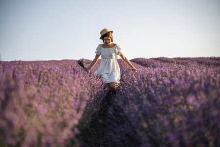 Lavender field happy girl in white dress with hat runs through a lilac field of lavender. Aromatherapy travelの写真素材