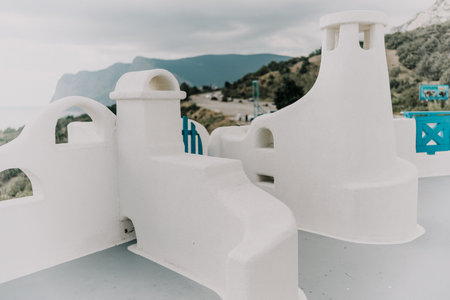 A white building with blue trim and a blue balcony. The balcony overlooks the ocean. The building is empty and the sky is cloudy.の写真素材