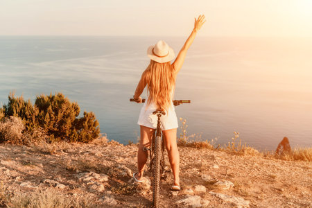 Woman travel bike sea. Happy woman cyclist sitting on her bike, enjoying the beautiful mountain and sea landscape, signifying the idea of an adventurous bike ride.の写真素材
