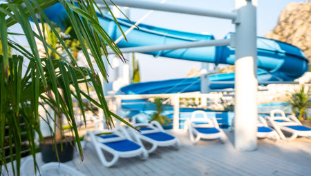 Water Slide Pool Loungers Resort - A blue water slide sits over a pool with white loungers and...