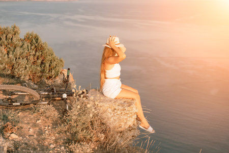 A woman cyclist on a mountain bike looking at the landscape of mountains and sea. Adventure travel on bike.の写真素材
