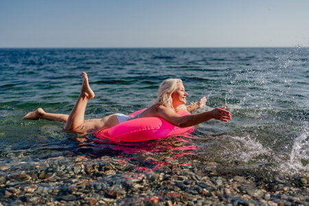 A woman is floating on a pink inflatable raft in the oceanの写真素材