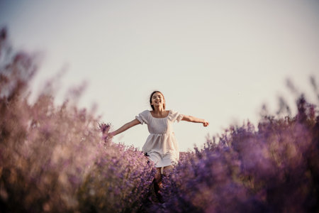 Lavender field happy girl in white dress with a scythe runs through a lilac field of lavender. Aromatherapy travelの写真素材