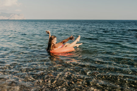 A woman is floating on a red inflatable tube in the oceanの写真素材