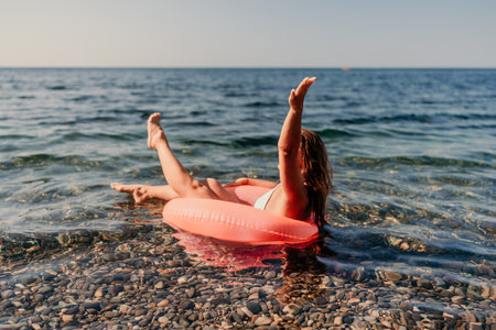 A woman is floating in a red inflatable tube in the oceanの写真素材