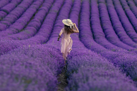 A woman is walking through a field of purple flowersの写真素材
