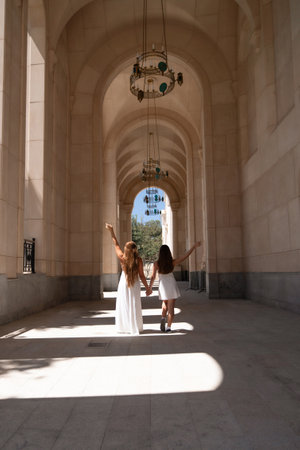 Women, Arches, Hallway - Two women walk through a long hallway with arched ceilings and bright light.の写真素材