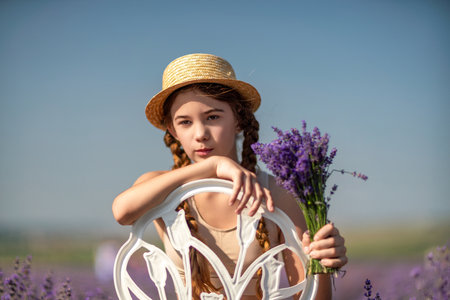 girl sitting field lavender and wearing a straw hat. She is smiling and holding a bouquet of flowersの写真素材