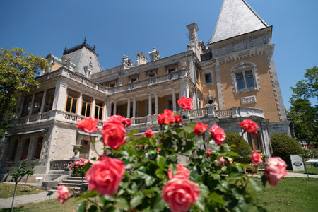 A large building with a lot of windows and a balcony. The balcony is covered with red roses.の写真素材