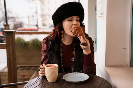 woman in a red dress is sitting at a table with a plate of food and a cup of coffee.の写真素材
