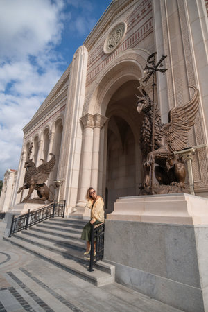 Woman, Building, Entrance - Tourist posing at the grand entrance of a historic building adorned with sculptures.の写真素材