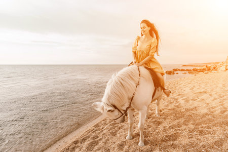 A white horse and a woman in a dress stand on a beach, with theの写真素材