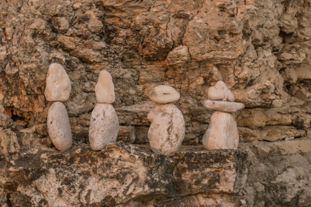Stone Cairns Rock Stacking Art Seacoast. Four small rock cairns, each with varying heights, are stacked on a rocky surface. The cairns are made of light-colored stones.の写真素材