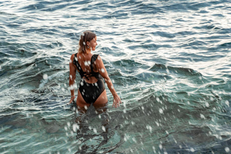 Woman Swimsuit Ocean Water - Woman in a black swimsuit wading in the ocean water.の写真素材