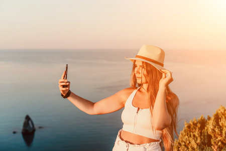 Selfie woman in a hat, white tank top, and shorts captures a selfie shot with her mobile phone...