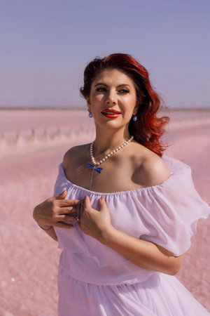 Woman Pink Salt Lake Dress - A woman in a white dress poses on a pink salt lake.の写真素材