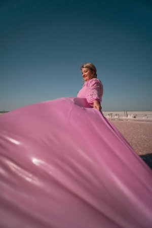 Woman Pink Dress Wind - Woman standing, holding out pink dress in the wind.の写真素材