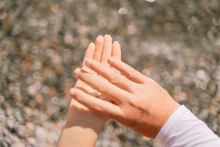 A person is holding a handful of nuts in their hand. The nuts are of different sizes and shapes, and they appear to be almonds. The person seems to be enjoying the nuts and is likely to eat them soon.の写真素材