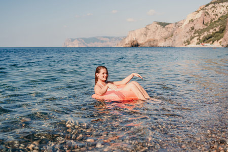 A woman is floating on a pink inflatable raft in the ocean