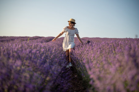 Lavender field happy girl in white dress with hat runs through a lilac field of lavender.の写真素材