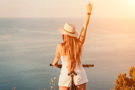 Woman travel bike sea. Happy woman cyclist sitting on her bike, enjoying the beautiful mountain and sea landscape, signifying the idea of an adventurous bike ride.の写真素材