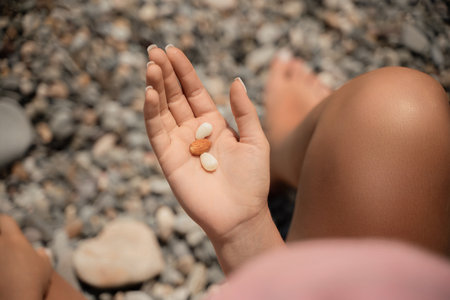 A person is holding a handful of nuts in their hand. The nuts are of different sizes and shapes, and they appear to be almonds. The person seems to be enjoying the nuts and is likely to eat them soon.の写真素材