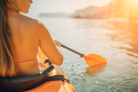 Woman in kayak back view. Happy woman with long hair in a swimsuit and hat floating in kayak on the sea. Summer holiday vacation. Summer holidays vacation at sea.の写真素材