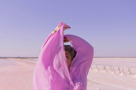 Woman Pink Salt Flats Dress - A woman wearing a pink dress poses in a pink salt flat.の写真素材