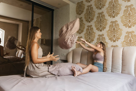 mom and daughter playing with pillows on a bedの写真素材